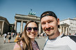 Young beautiful couple making selfie against the background of the Brandenburg Gate in Berlin in Germany.
