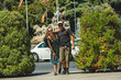 © Daniel Rodriguez - Young happy and bouncing couple on holiday in europe in Madrid, Spain. Man and woman on the sidewalk of the street surrounded by trees and bushes and Spanish flags