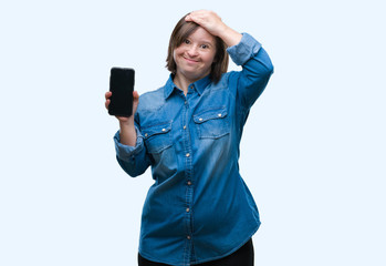 Sticker - Young adult woman with down syndrome showing smartphone screen over isolated background stressed with hand on head, shocked with shame and surprise face, angry and frustrated. Fear and upset