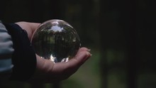 Close Up Of A Young Female Hand Holding A Crystal Ball Reflecting Landscape In An Autumnal Forest
