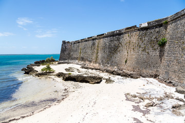 Wall Mural - Empty yellow-white sand sea beach near wall of Fort São Sebastião (San Sebastian, Sao Sebastiao), Mozambique island (Ilha de Mocambique), Indian ocean coast, Moçambique. Portuguese East Africa