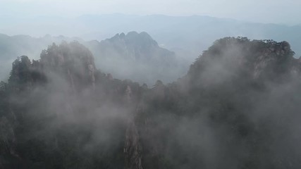 Wall Mural - tilting drone footage of breathtaking mountain landscape covered in fog and mist, spectacular view o