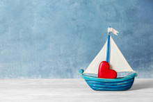 Toy Ship With Red Decorative Heart On Table. Space For Text