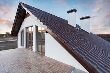 Side view photo of small cozy comfort new house with brown roof large mansard windows and two white chimney on top