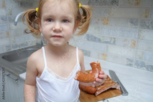 Funny Hungry Baby Girl Eats Smoked Sausage And Pork Ribs In The Kitchen
