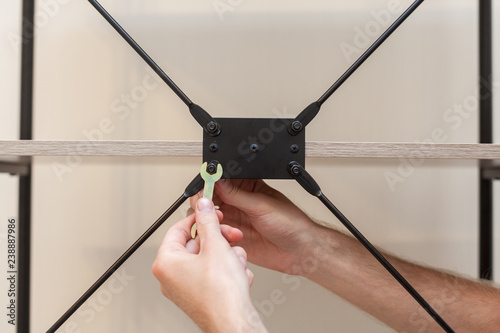 Fotografie, Tablou The handyman adds the bookcase construction by screwing the bolts with a hexagon