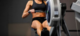 Powerful attractive muscular woman CrossFit trainer do workout on indoor rower at the gym
