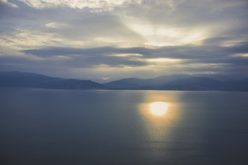 Wall Mural - abstract soft focus nature landscape with calm sea water and mountain horizon background in morning sun rise time and foggy cloudy weather