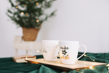 Wall Mural - Cozy bedroom with coffee mugs and book in bed. Christmas still life. Holidays, Christmas and New Year concept  