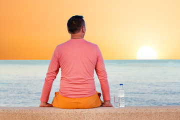 Wall Mural - man sitting on beach and looking at sea