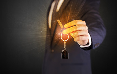 Formal man hand over shiny keys with dark background
