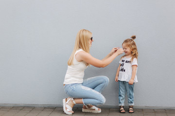 Beautiful mothe with her daughter. Blond hair female. Gray background. Best friends