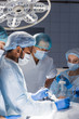 © alfa27 - Team of Professional surgeon, assistants prepare a patient to invasive surgery in the Hospital Operating Room. Surgeons consulting with each other while using instruments.