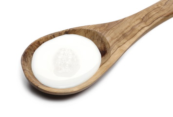 Wall Mural - Spilled milk puddle in wooden spoon isolated on white background