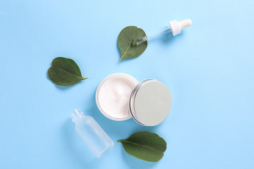 Wall Mural - Moisturizing care skincare face cream for healing complicated troubled skin type in an open jar with visible texture. Copy space, close up, background, flat lay, top view. Eucalyptus leaf decoration.