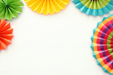 Festive And Party Background With Colorful Paper Circle Fans Over Wooden White Background. Copy Space.