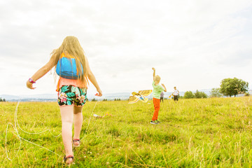 Sibling fly kites in the meadow, hiking