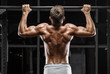 Muscular man doing pull up on horizontal bar in gym, working out. Strong fitness male pulling up, showing back, outdoors