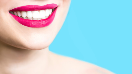 Wall Mural - Close-up of a smiling woman with healthy white teeth, red lipstick, clean skin. Dentistry concept. Blue background. Copy space. 