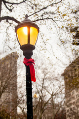 Wall Mural - Lamppost with red bow decorated for Christmas with Flatiron Building in background seen from Madison Square Park, New York City Manhattan