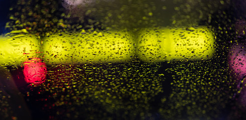 Wall Mural - background. defocus. raindrops on the glass flow down. colored bokeh of street lamps, cars and shop windows.