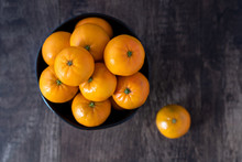 Bunch Of Satsuma Oranges In A Black Bowl On A Wood Background