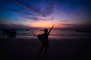 Wall Mural - Woman dancing on sand beach romantic sky at sunset, rear view, golden sunlight, real people. Indonesia, Kei islands, Moluccas Maluku