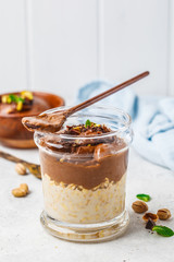 Wall Mural - Overnight oatmeal with milk and chocolate mousse in glass on a white background.