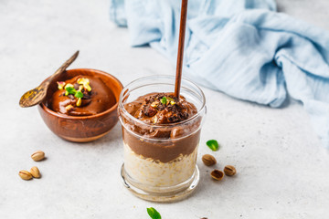 Wall Mural - Overnight oatmeal with milk and chocolate mousse in glass on a white background.