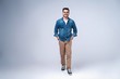 © opolja - side view of a smiling young casual man walking , on gray background.