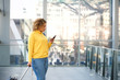  travel woman looking at mobile phone at station
