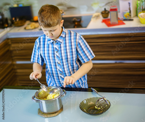 The Boy Stirs The Mashed Potatoes In The Kitchen With Two Spoons At Once Stock Photo Adobe Stock