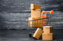 A Supermarket Cart Loaded With Cardboard Boxes. Sales Of Goods. Concept Of Trade And Commerce, Online Shopping. High. Delivery Order. Purchasing Power Of The Population And The State Of The Economy