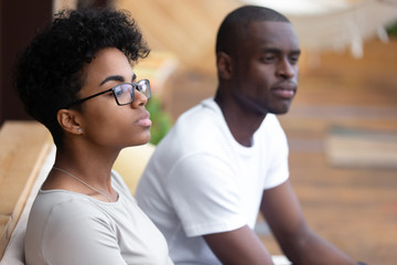 Serious African American woman sitting in cafe, looking in distance, bored female at boring meeting with colleague, bad first date, offended girlfriend ignore black boyfriend, people waiting order