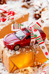 Christmas and New year background with toy car present with ribbon. Balls, pinecones and different decorations on snow.