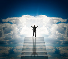 A Man In A Suit With Arms Outstretched On A Stone Staircase To The Clouds And Light. Stairway To Heaven.