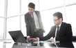 © ASDF - Manager and employee discussing financial documents
