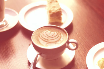 Coffee in ceramic cup with beautiful foam on coral background. Concept of breakfast.  Color of the year 2019 concept.