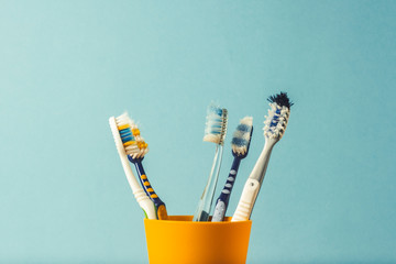 Wall Mural - Many toothbrushes in a plastic cup on a blue background. The concept of changing toothbrushes, oral hygiene, dentistry. Big and friendly family