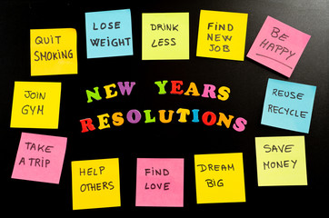 Colorful New Year resolutions and sticky post its notes with popular goals on chalk blackboard