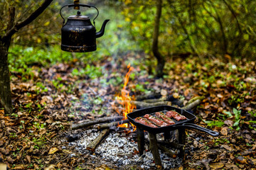 Wall Mural - CookingOld kettle and smoke in sunshine meat by the campfire