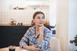 © shurkin_son - Indoor image of attractive serious mature sixty year old housewife wearing casual checkered shirt having coffee, sitting at kitchen table with mug and looking sideways with thoughtful expression