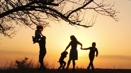 Wall Mural - Silhouettes of family spending time together in the meadow near during sunset