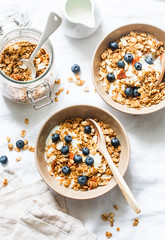 Homemade peanut butter granola with greek yogurt and blueberries on a light background, top view. Healthy energy breakfast or snack. Flat lay