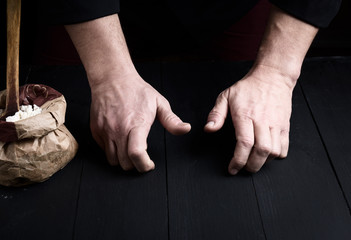 two male hands over a black wooden table