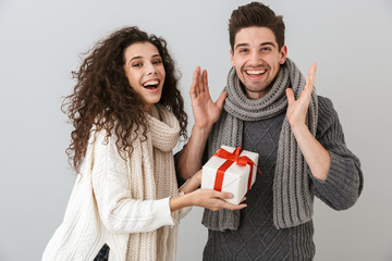 Sticker - Image of attractive man and woman rejoicing while standing with present box, isolated over gray background