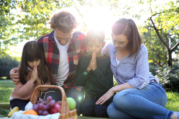 Family praying before meal in park