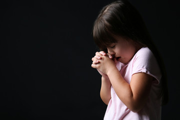 Wall Mural - Portrait of praying girl on dark background