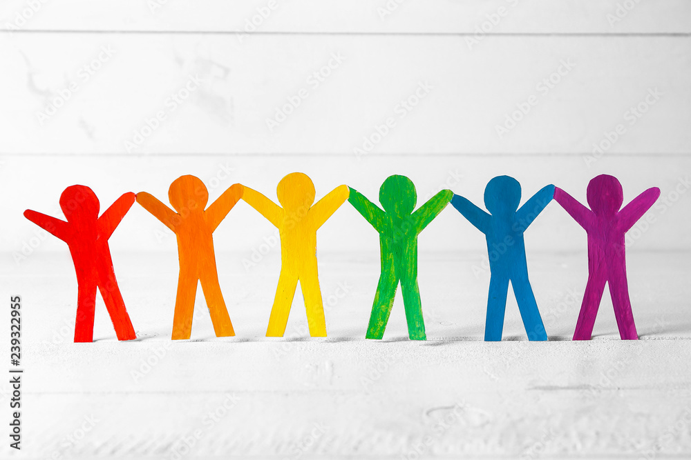 Rainbow paper human figures on white table. LGBT concept