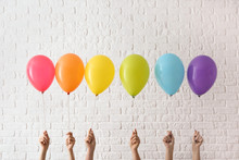Women Holding Rainbow Air Balloons On Light Background. LGBT Concept